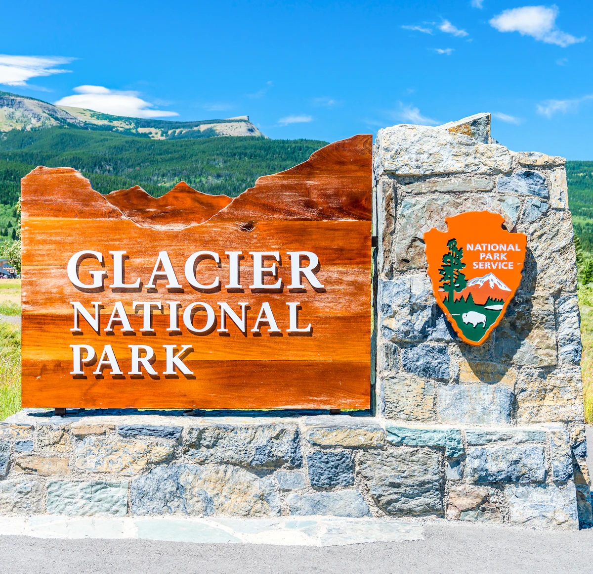 ป้ายทางเข้า Glacier National Park ตัวอักษร Clarendon บนแผ่นไม้