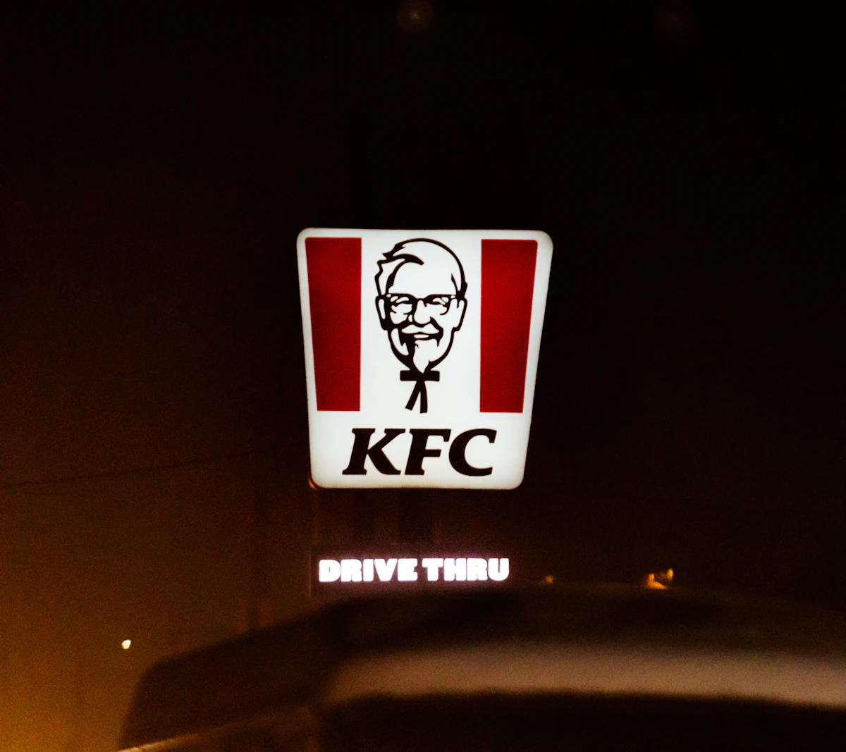 ป้ายไฟ KFC ส่องสว่างยามค่ำคืน โลโก้ตัวอักษรและภาพผู้พันแซนเดอร์ส