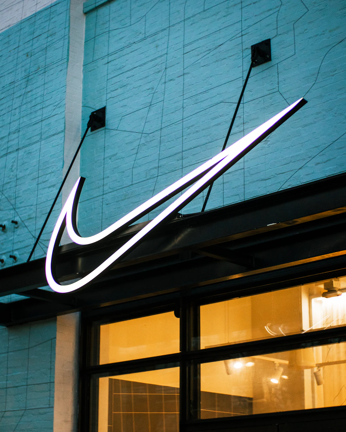 ป้ายนีออน swoosh ของ Nike บนอาคารริมถนน โลโก้ที่อ่านออกแม้ไม่มีชื่อแบรนด์